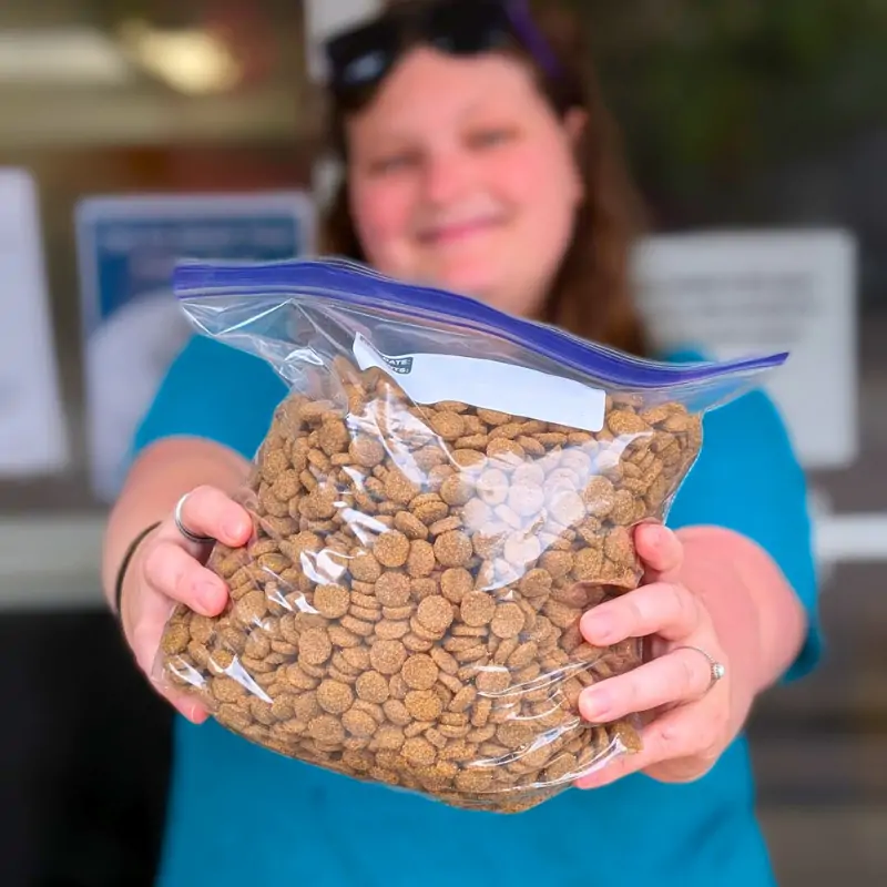 community support community support volunteer holding a bag of dog food for community food pantry