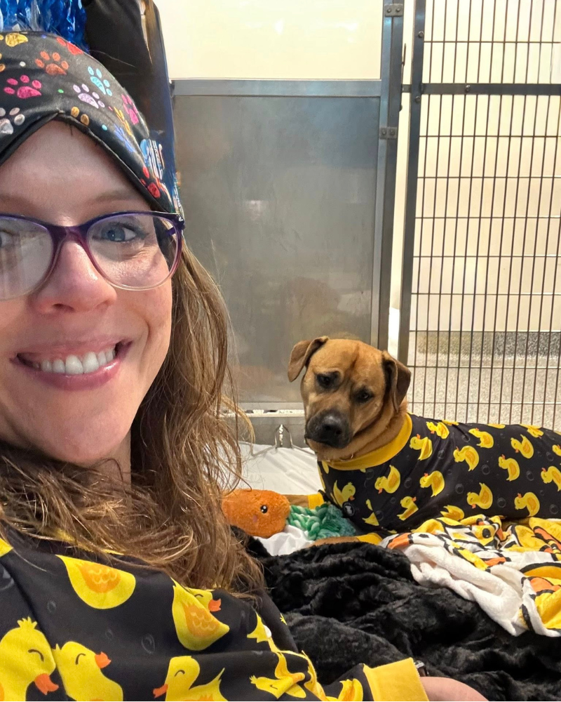 woman and dog in matching pjs inside dog kennel during shelter slumber pawty