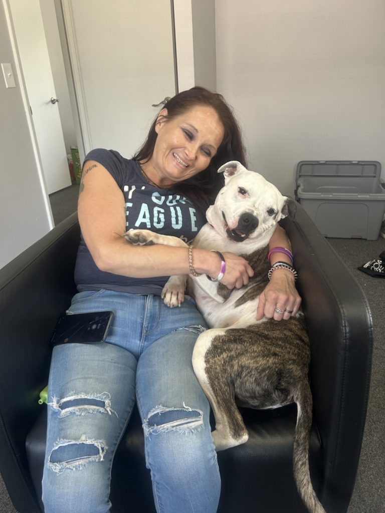 dog Robert with amanda at sunstone recovery program snuggling on couch together smiling