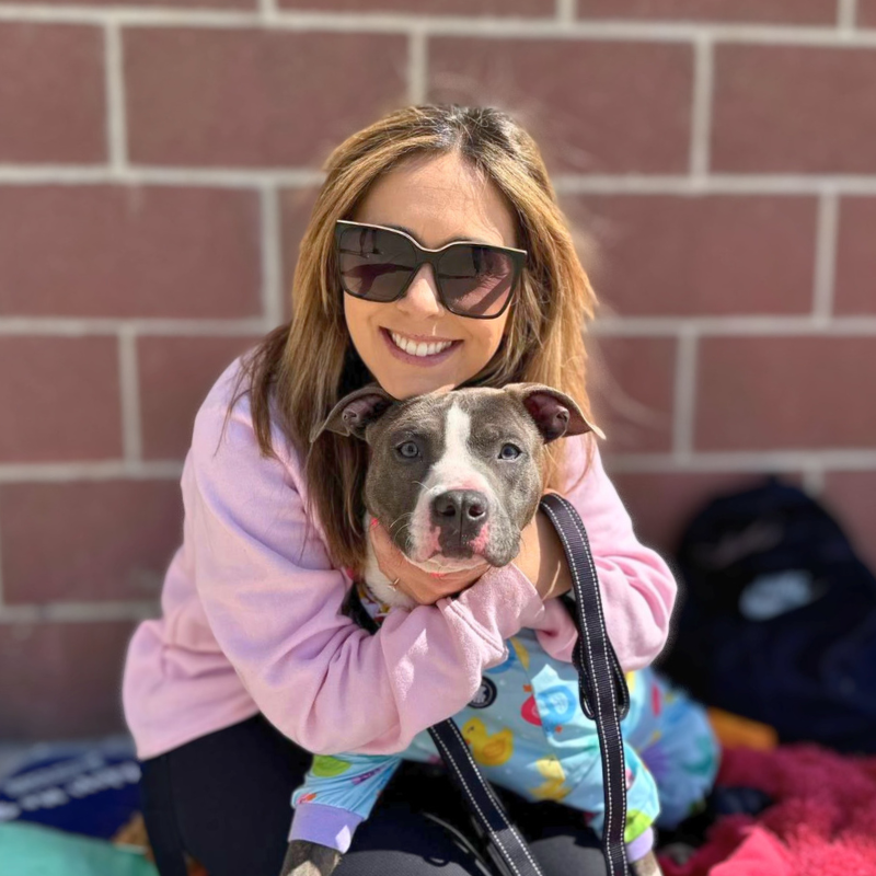 woman posing with adoptable shelter dog at adoption event